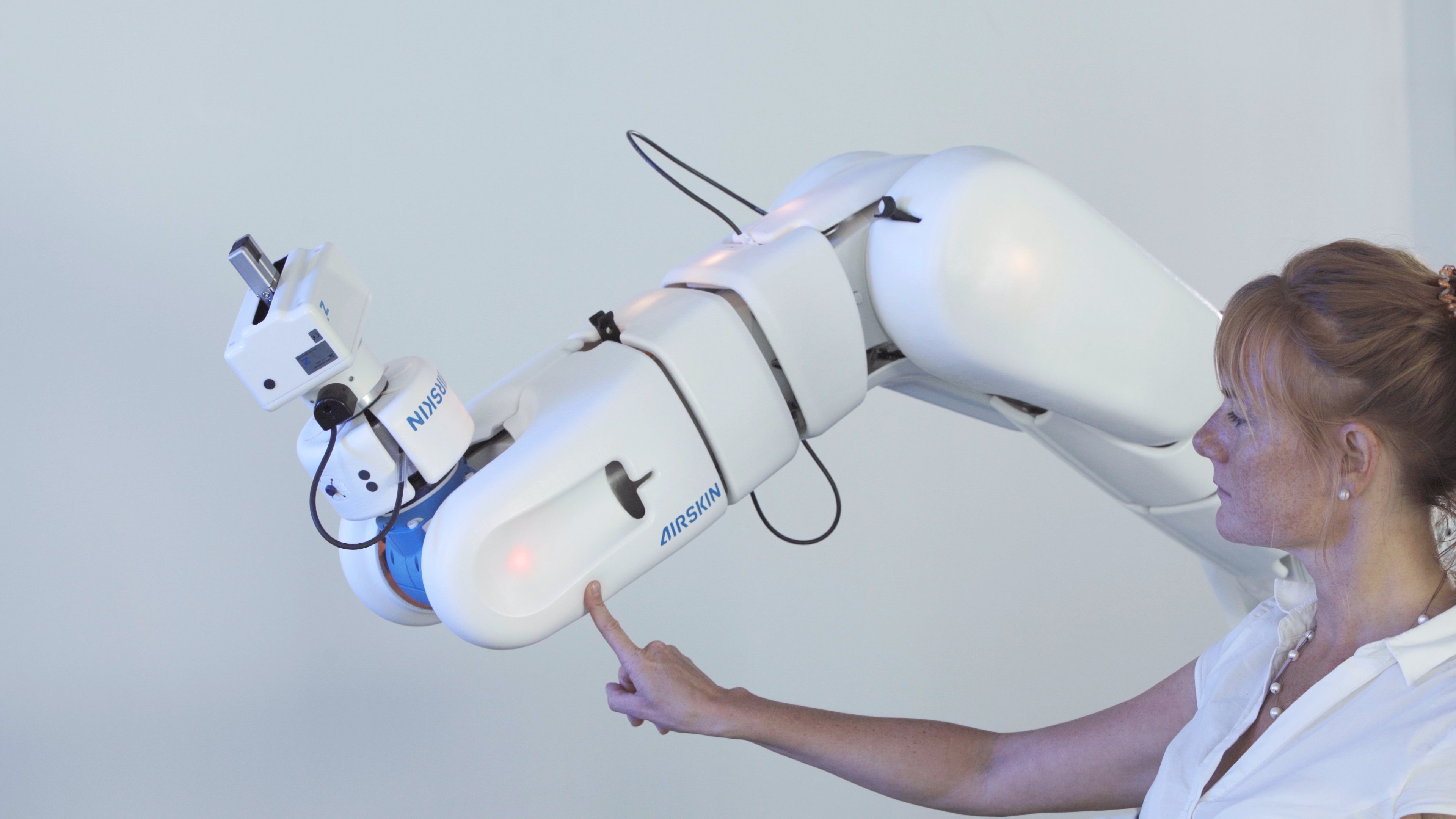 Girl touching industrial collaborative robot safely with her index finger