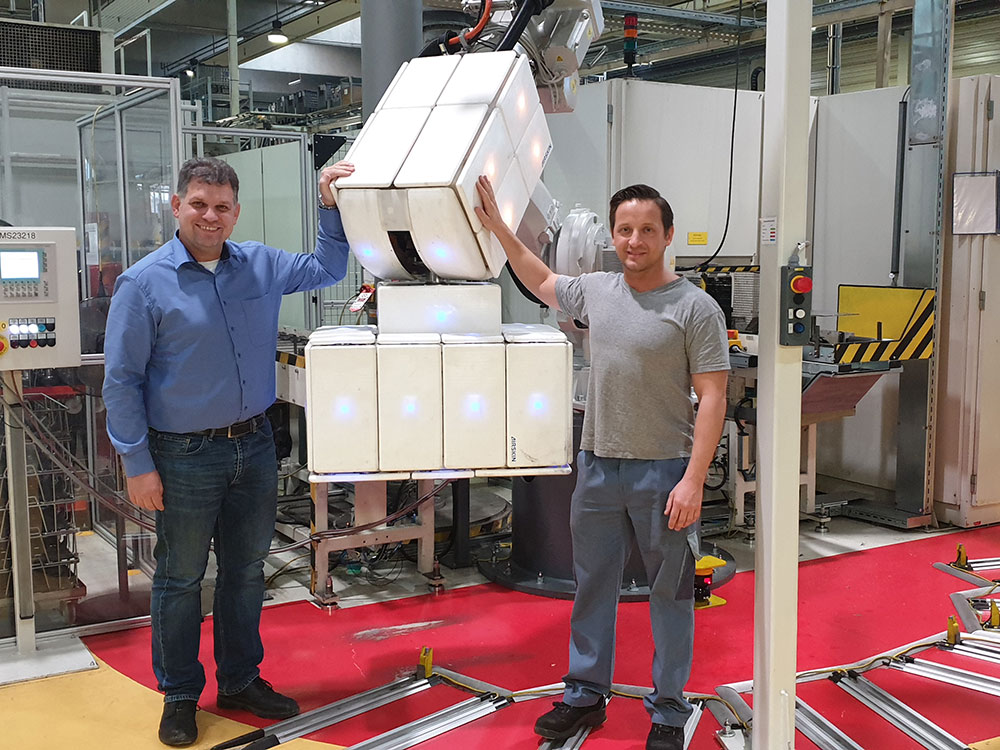 Fenceless collaborative robot covered with a robot safety skin and two human workers touching it 