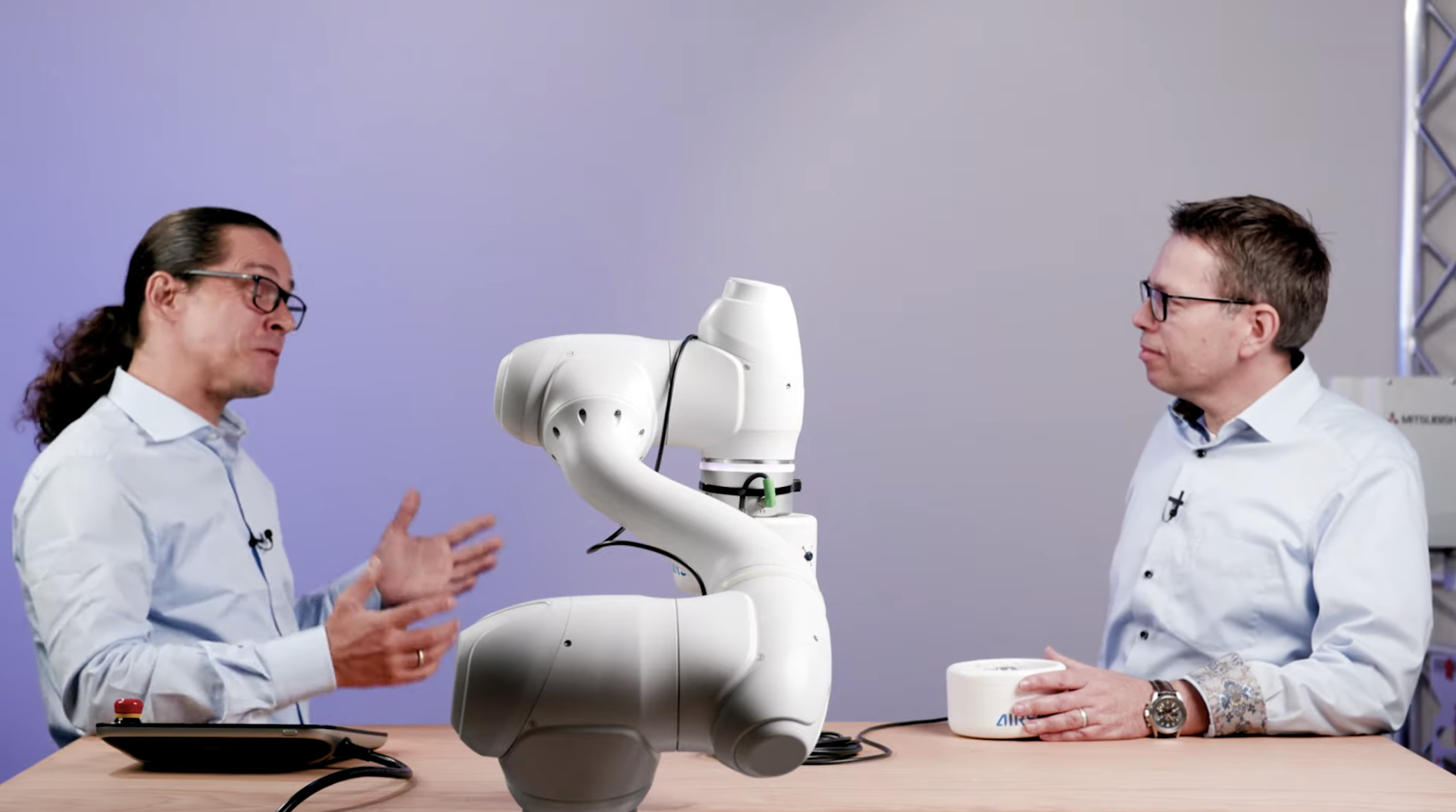 Two men talking about a collaborative robot in a studio setting